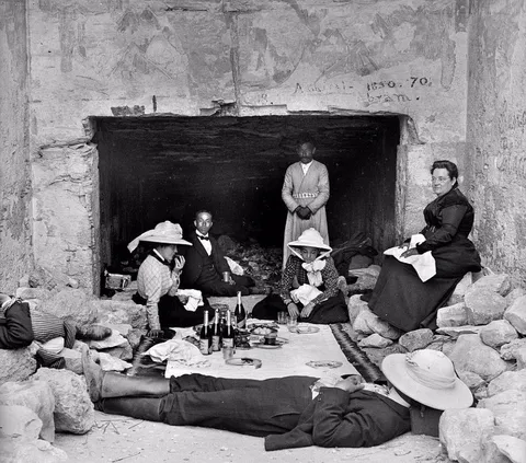 European tourist sleeping and eating at the door of one of the pyramids, circa 1900s.