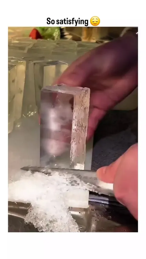 Shaving clear ice with a knife.