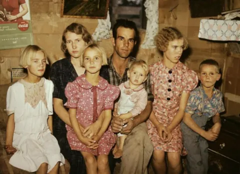 Family during the depression with girls in flour sack dresses. Circa 1930s.