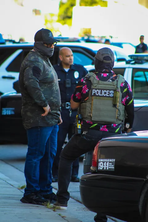 LAPD won’t enforce mask ban; here’s ICE in a POLICE mask, lounging on an LAPD car during arrest [OC]