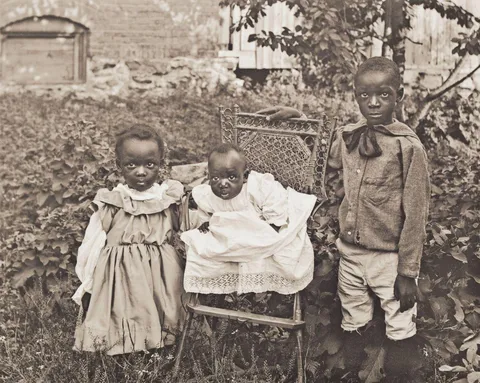 Group of children pose for their photo with the little newborn looking totally confussed as to what is going on.Circa 1901