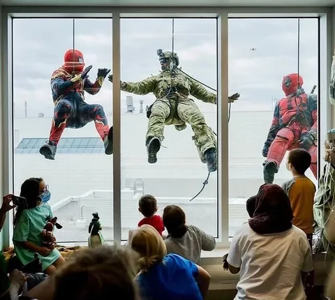 Tactical team personnel dressed up as Spiderman and Deadpool rappel down the walls of the Montreal Children's Hospital