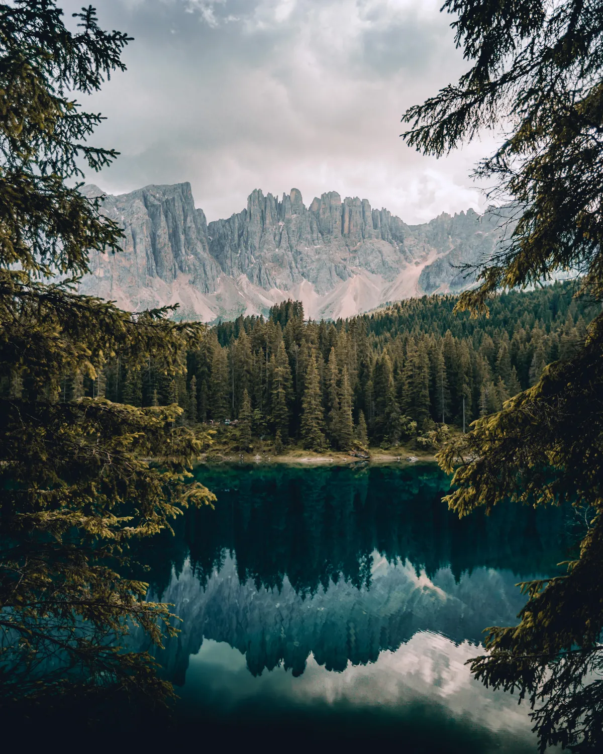 Calm water and jagged mountains. Reflections at Lago di Carezza, Italy. [OC][3747×4684]