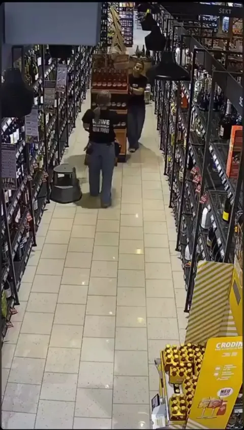 Two people attempt wheeling a grocery display only secured on one side. Why? (No Audio)