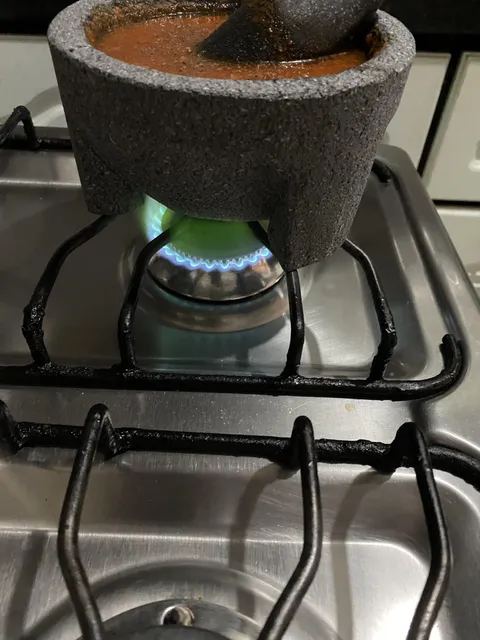 my mother is making sauce in a mortar made with volcanic rock and the flame on the stove turned green