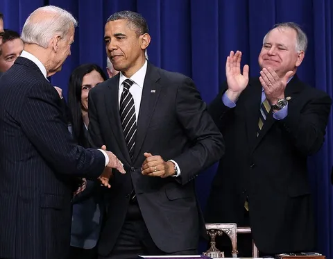 Tim Walz standing behind and applauding President Obama as the STOCK Act is signed into law
