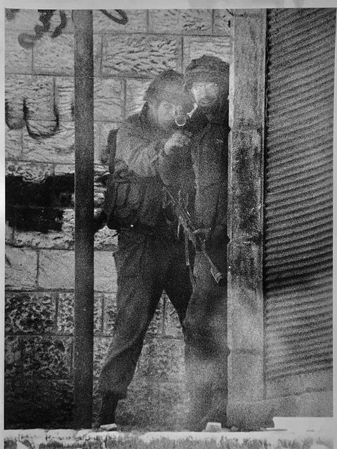 Spanish journalist Javier Bauluz snaps a photo as IDF soldier smile and aim a rifle at him. (First Intifada - Nablus, Palestine | Jan 31, 1988)