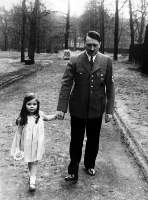 Adolf Hitler walking with Helga Goebbels, who was later poisoned with cyanide by her parents together with her siblings in Hitler's bunker in 1945.