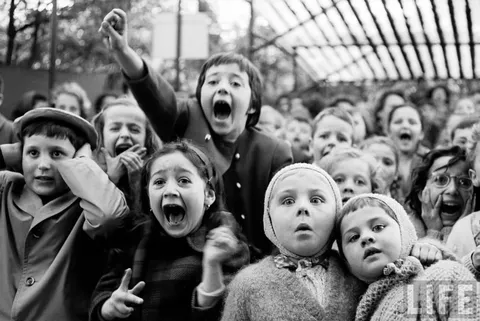 This picture was taken by Alfred Eisenstaedt at a children's puppet show. He caught this picture of the children at the exact moment the dragon was slain. Tuileries, France, 1963.