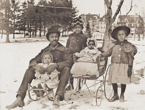 Father poses with his children in the snow, holding one of his smallest one close to him, Worcester, circa 1900s