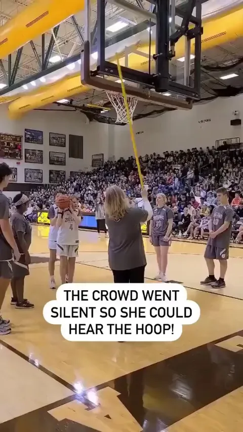 A blind girl shooting a basketball.