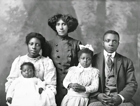 Family poses together for their professional studio photo, 1900-10s. crisp glass negative
