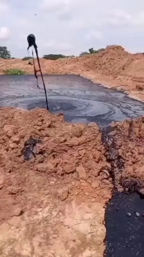 Huge gas bubble bursts through a dark mud pool