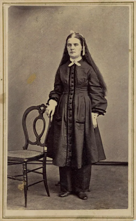 Woman in knee-length dress and pants, ca. 1860s. Any ideas if the clothing and hairstyle indicate a religious or social community? From a bound photo album I bought years ago. Subject and photographer unknown. [1457 x 2361]