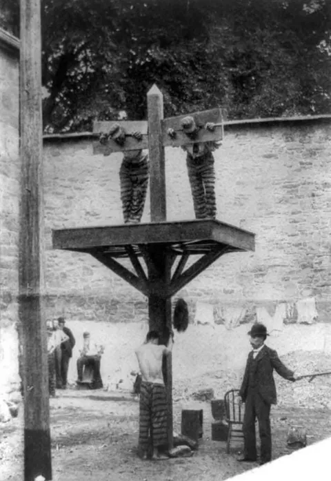 Two men in a pillory and one on a whipping post in prison in Delware. (1907)