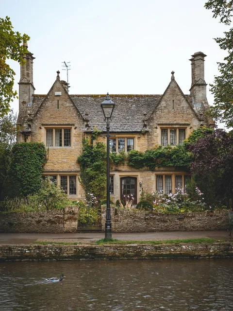 Stone cottage along the River Windrush flowing through the village of Bourton-on-the-Water, Gloucestershire, England.