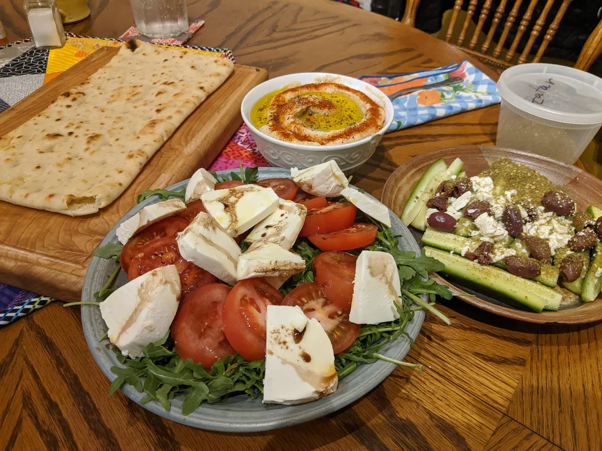 Mediterranean spread - arugula caprese, homemade hummus, Persian cukes with feta, kalamata olives, and za'atar, and flatbread