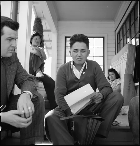 Japanese-American farmer Near San Jose California completes the leasing his acreage, buildings, and equipment for the duration of his evacuation to a War Relocation Authority center. His sisters can be seen in the background. 27 of March 1942.