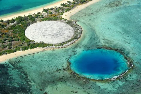 Runit Island.  The 115m wide concrete dome is used to seal contaminated waste from nuclear bomb testing in the Marshall Islands in the 1950s.  The hole next to it is from a nuke test.
