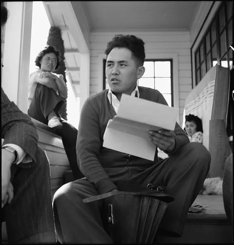 Japanese-American farmer Near San Jose California completes the leasing his acreage, buildings, and equipment for the duration of his evacuation to a War Relocation Authority center. His sisters can be seen in the background. 27 of March 1942.