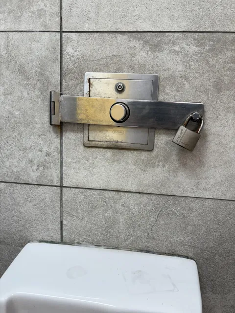 This urinal flush has a lock over it to prevent theft