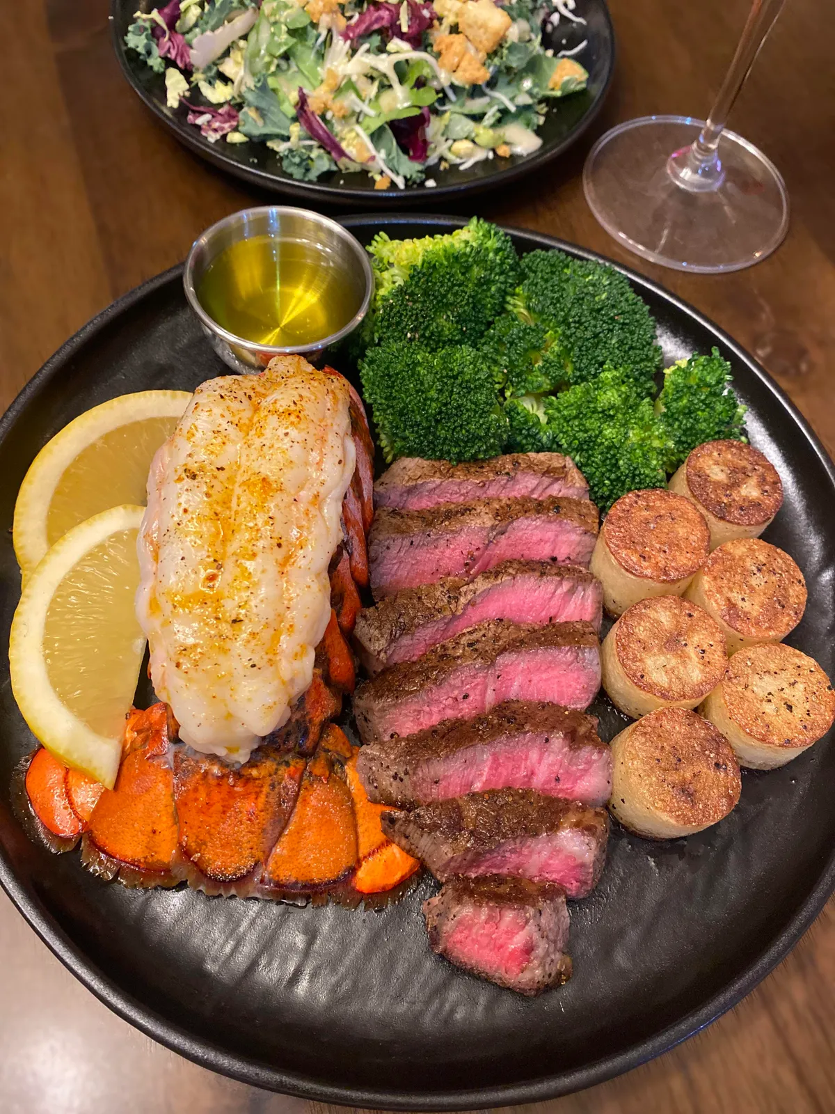 [OC] 5oz. Filet mignon, 3.75oz lobster tail with melted ghee and lemon wedges, steamed broccoli, mini fondant potatoes, and side salad- $20 for my meal