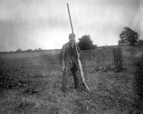 A man holding a Punt Gun, an oversized shotgun once used for duck hunting. Capable of killing more than 50 birds in a single shot, it was outlawed in the late 1860s.