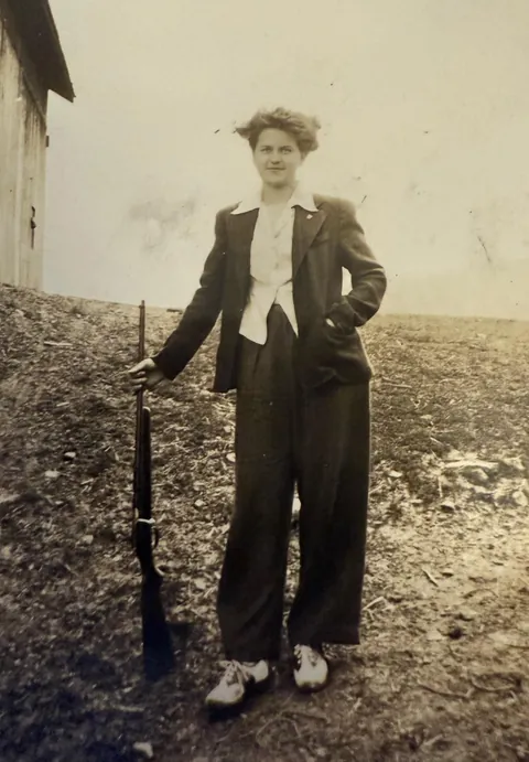 My mom at 17 with a bolt action rifle. 1941.