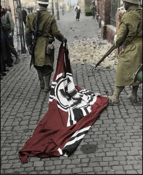 Two french colonial troop parading with a German flag,liberation of France 1944