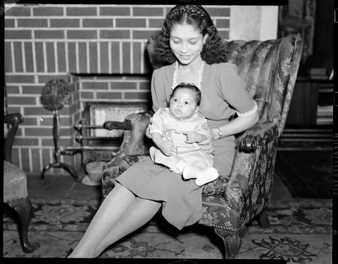 Little chubby baby and her mother posing thogether in the living room, circa 1940s. Agfa Safety film.