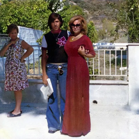 Grandma with my uncle in the 70s (and a random lady judging their outfits)