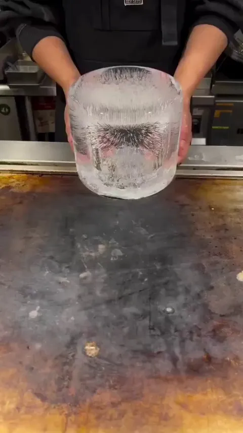 Cleaning a scorching hot griddle with ice.