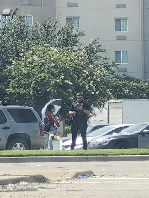 A cop in Dallas, TX writing a ticket to a woman selling flowers at an intersection