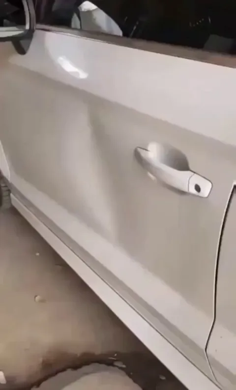 Using packing tape to remove a car dent.