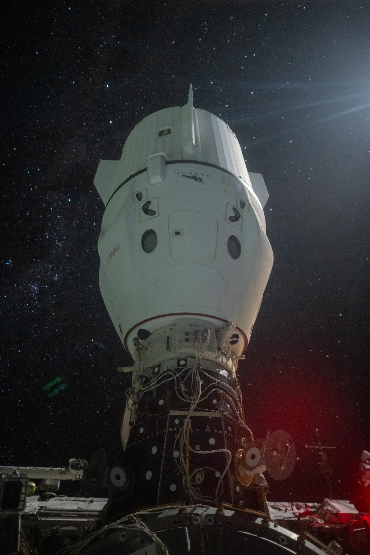 An out of frame moon creates a lens flare and illuminates the Dragon perched atop the International Space Station.

Photo taken looking out Starliner’s window. 

1/1.3 s exposure, 2000 ISO, f1.4, 24mm lens