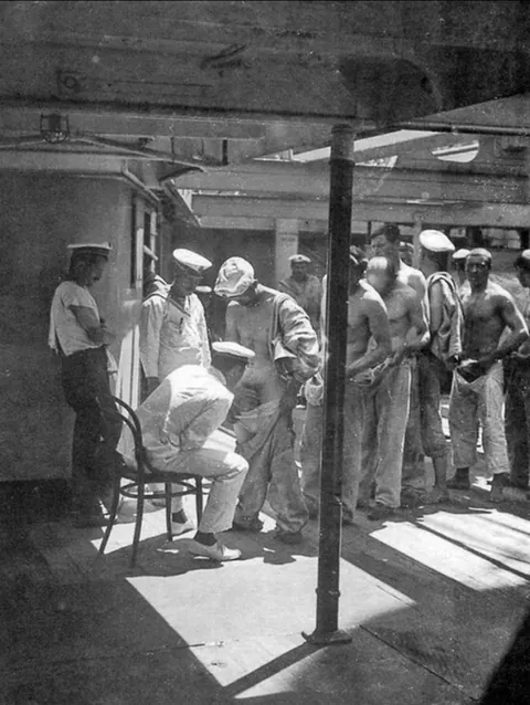 A Naval Doctor examines sailors returning from shore leave (1910). This prevents the spread of pubic lice (crabs) and check for STDs.