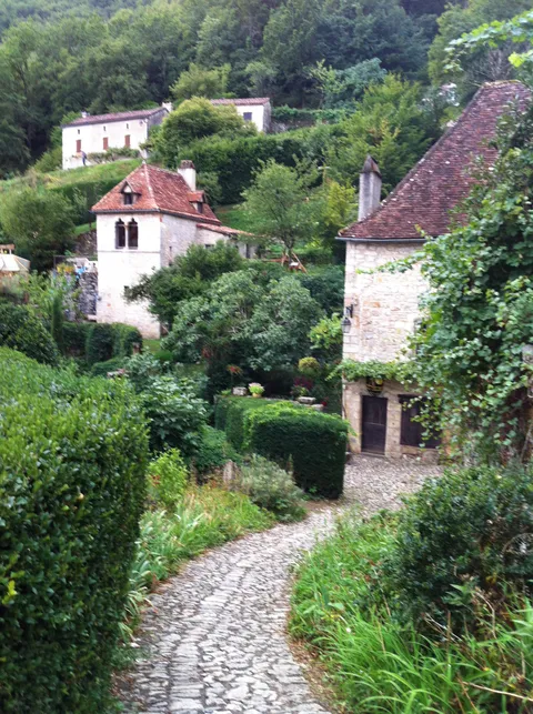 Surrounded by lush green and worn stone in this French village [OC]