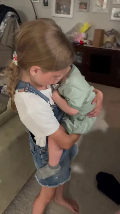 Little boy won’t let go of his sister.