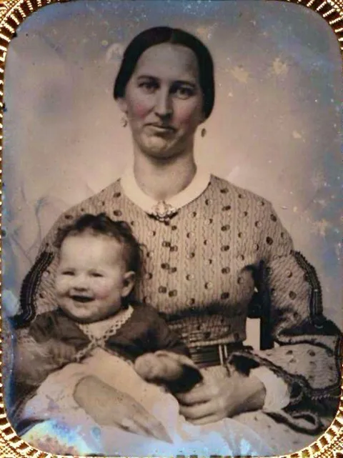 Daguerreotype shot at the right moment. Captures the moment when a baby burst laughing and her mom fight to no follow suit, 1850-60s.
